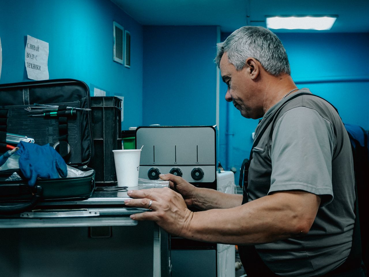 our-value A male technician works on a machine in an industrial environment, focused on adjusting controls.