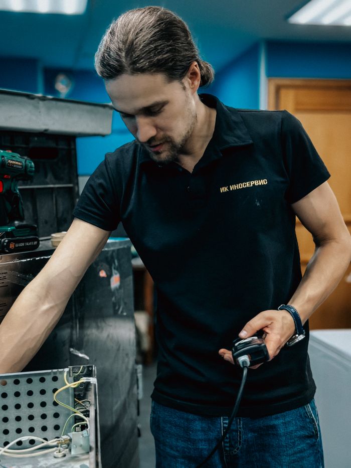 A male technician focuses on repairing kitchen equipment in a workshop setting, showcasing expertise.