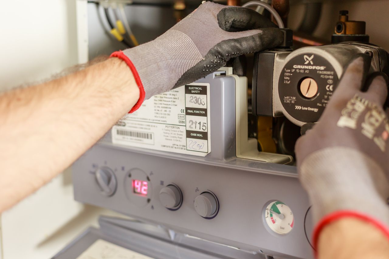 our-mission Close-up of hands adjusting a boiler system with precise instrumentation, showing maintenance work.